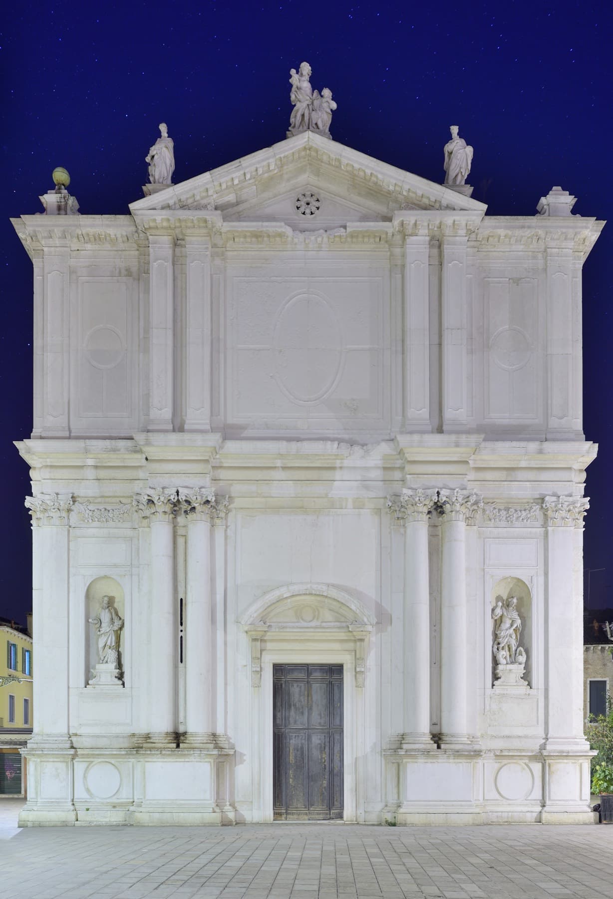 A classical stone facade of a public building, lit at night against a dark sky